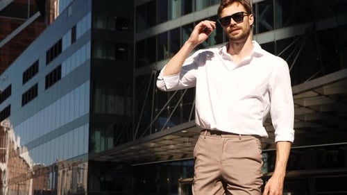 Confident Man Posing Near Modern Urban Buildings