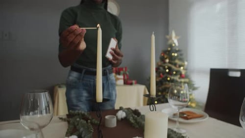 Person Lighting Candles on Christmas Table