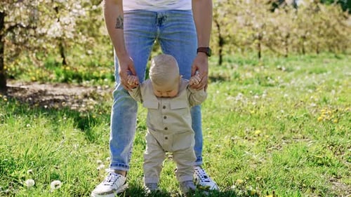 A bumblebee is flying near the little kid learning to walk outdoors.