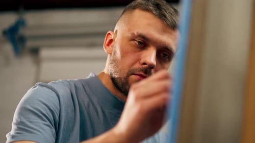 Closeup of a Young Artist in Blue Tshirt in an Art Studio Working on a Painting