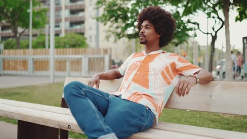 man sitting relaxed on park bench looking away