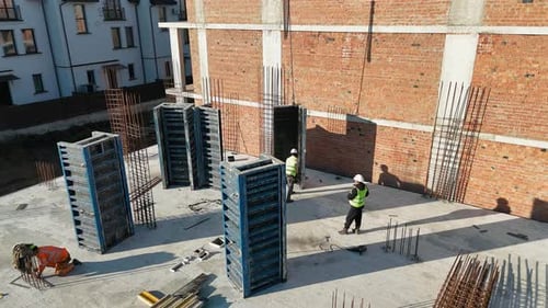 Arbeiter auf der Baustelle mit Stahlrahmen und Backsteinwänden Bauarbeiter beim Aufbau von Stahl