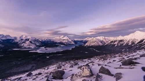 snow covered peaks in the rocky mountains with a frozen lake at sunset