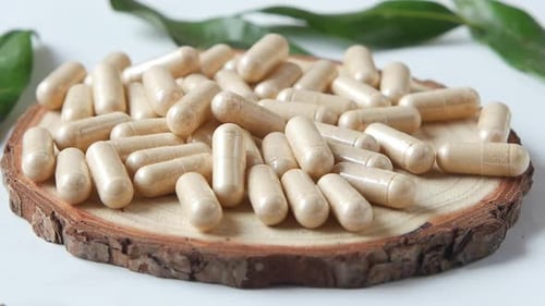 Top View of Herbal Medicine Capsule Dropping on White