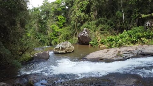 Beautiful sequence shot of drone descending a waterfall very close to the water, with trees and natu