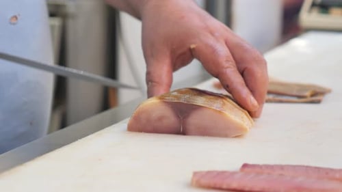 Chef Skillfully Slicing Fish for Sushi