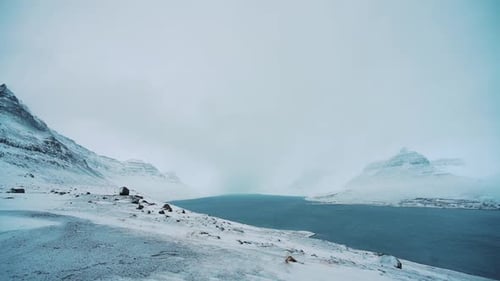 Slow motion pan across ice blue lake, icy arctic sea at westfjords fjord, mountain in Iceland