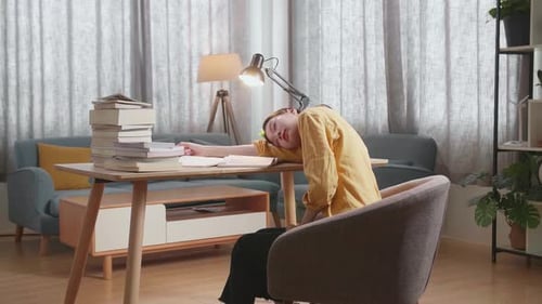 Side View Of Young Asian Female Studying At Home Yawning And Sleeping While Reading Books
