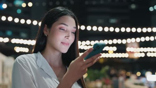 Young Girl Responding To SMS With Voice Message While Sitting In Night Bar