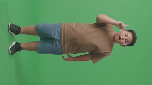 Full Body Of Asian Boy Thinking Then Raising His Index Finger While Standing On Green Screen