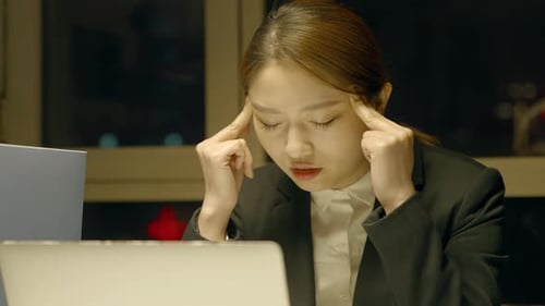 Tired Female office worker portrait of a young woman suffering from headache and discomfort while wo