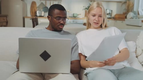 Man and woman using laptop and reading papers