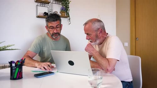 Two Men Discussing Information on Laptop at Home