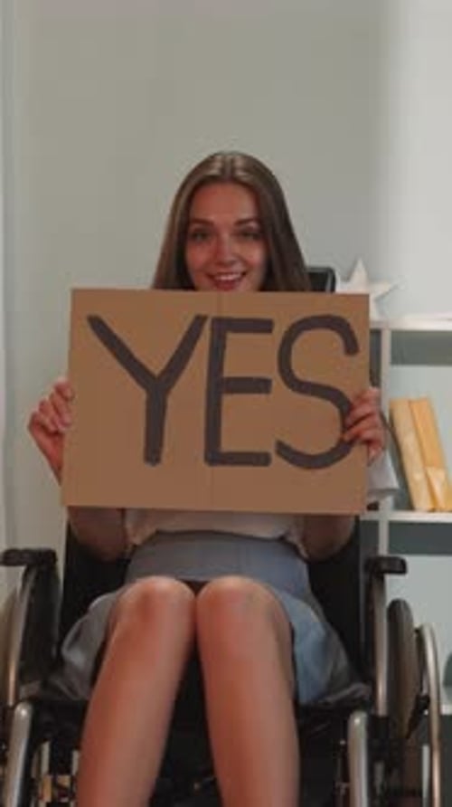 Young Woman in Wheelchair Holding Sign That Says Yes