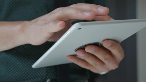 Businessman scrolls through digital tablet in modern office setting
