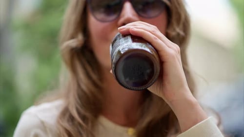 Gros plan d'une brune, d'une jeune femme buvant un thé kombucha à l'extérieur