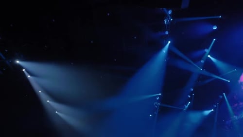 Hellblaue und weiße Bühnenlichter beleuchten den dunklen Konzertsaal