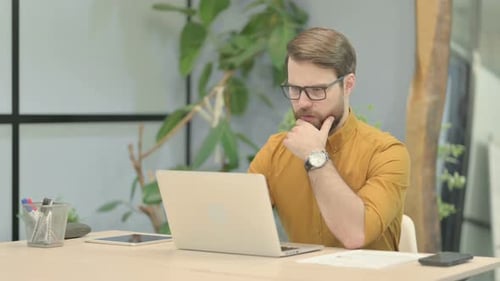 Young Adult Man Working with Laptop in Office