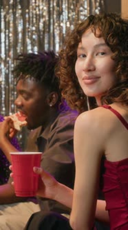 Vertical Portrait of Joyful Young Woman with Red Paper Cup Visiting Party
