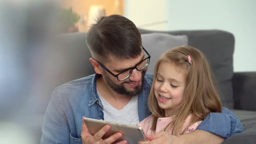Father and Daughter Looking at Tablet Together at Home