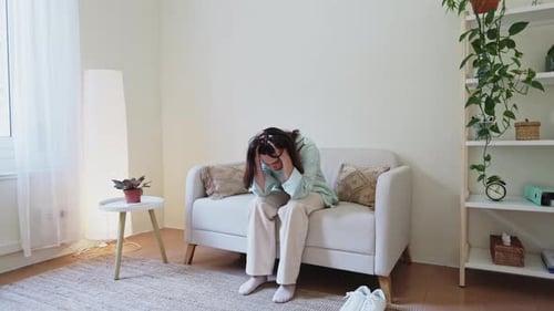 Woman Sitting on Couch Looking Sad