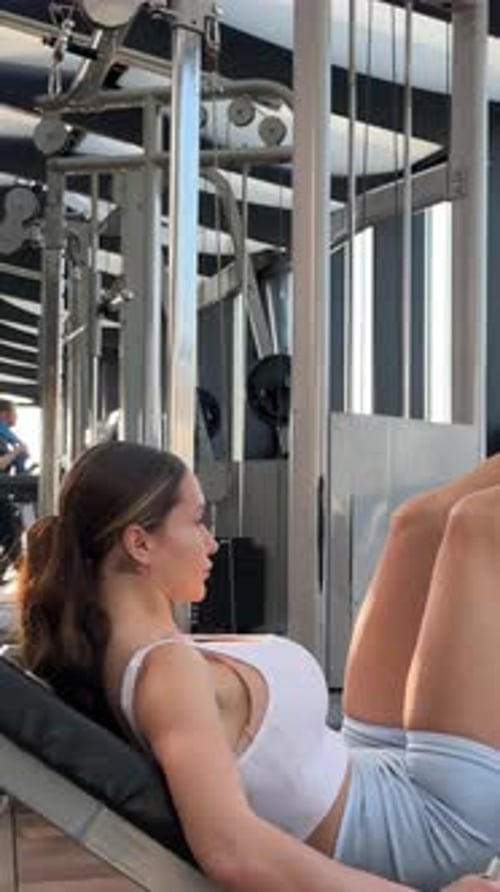 Beautiful Woman Sporty Girl Exercising Using Leg Press Machine at the Gym