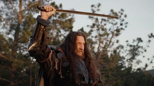 Man With Sword in Forest Raising Weapon