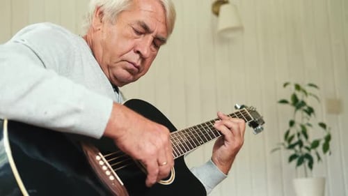 Senior Man Plays Acoustic Guitar at Home