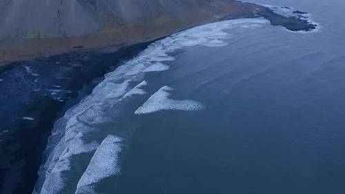 Waves of the Atlantic ocean break on black sand beach in Stokksnes near Vestrahorn mountain in Icela