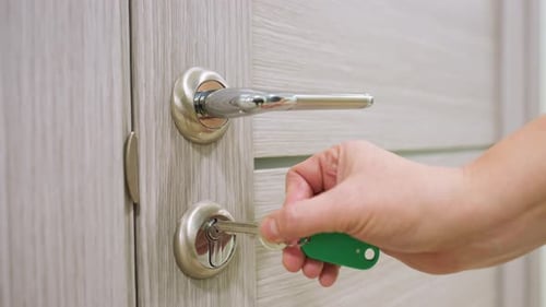 Close Up of Female Hand Unlocking Modern Wooden Door with Key Indoors