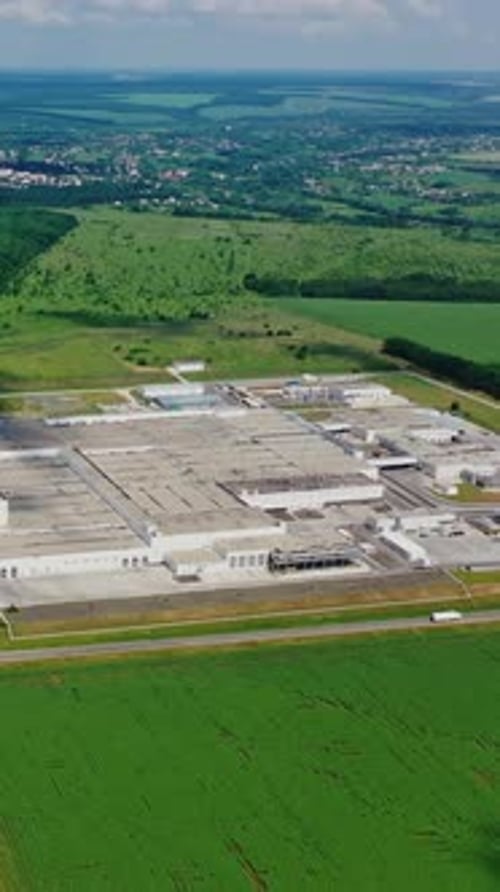 Modern factory surrounded by nature. Large area of industrial complex among green fields.