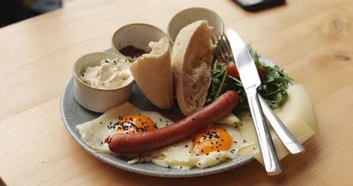 Breakfast Plate of Fried Egg Greens Salad with Tomato Sausage Buns and Sauces