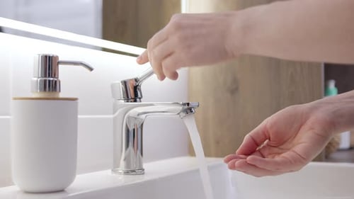 Hands of Unrecognizable Young Woman Squeeze Soap From White Dispenser in Light Bathtub and Washes