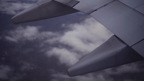 Looking out window of high altitude commercial airline at ground with a rack focus to clouds.