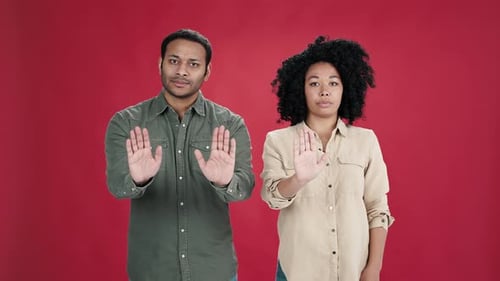 Indischer Mann und Afroamerikanerin zeigen Stop-Geste