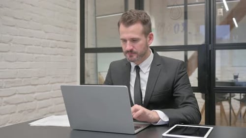 Excited Businessman Working in Office on Laptop