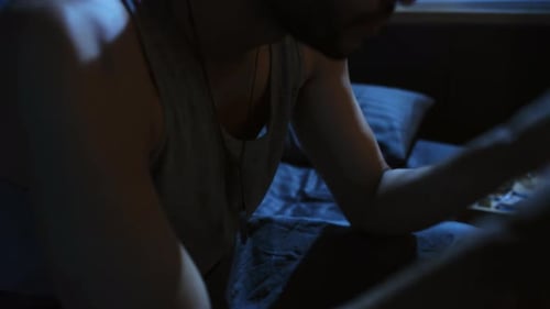 Man Expressing Anguish in a Dimly Lit Bedroom