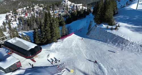 A ski resort in a mountain range dotted with pine forests on a clear sunny day