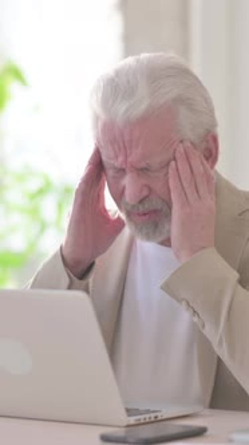 Senior Man with Headache Using Laptop at Desk
