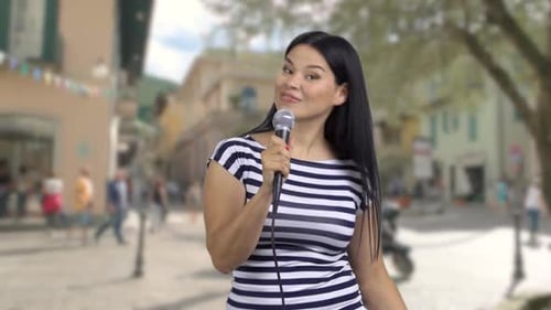 Woman Singing with Microphone in Urban Setting