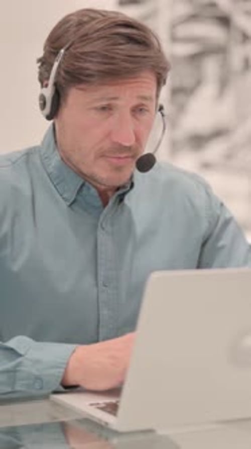Adult Man with Headset Talking with Customers Online in Call Center, vertical