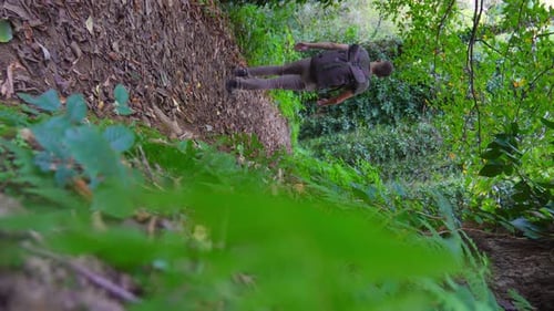 Mann oder Typ, der auf einem Fußgängerweg durch den grünen Wald läuft.