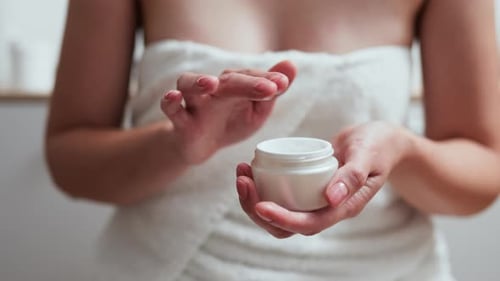 Close Up Of A Woman's Hand With Her Fingers Takes A White Cream To Moisturize The Skin Of Her Body