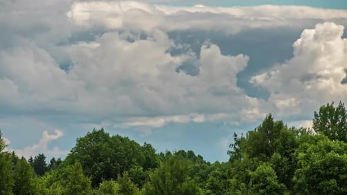 Shot of white fluffy clouds slowly float through the blue daytime sky in timelapse. Cloud movement o