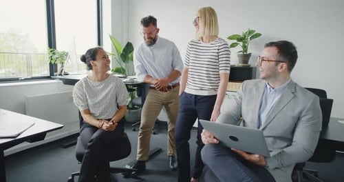 Laughing businesspeople collaborate on a successful project in a modern office