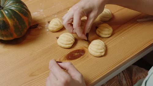 Person Making Pumpkin-Shaped Cookies on Table