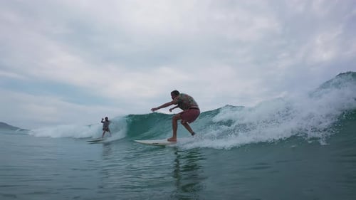Surfers Ride Waves in Ocean on Overcast Day