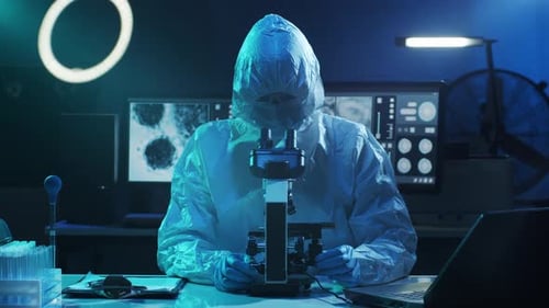 Scientist in Hazmat Suit Using Microscope in Lab