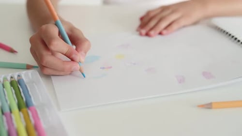 Child Draws with Colored Pencils at Table