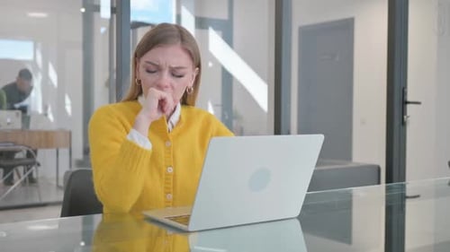 Coughing Young Woman Using Laptop in Office